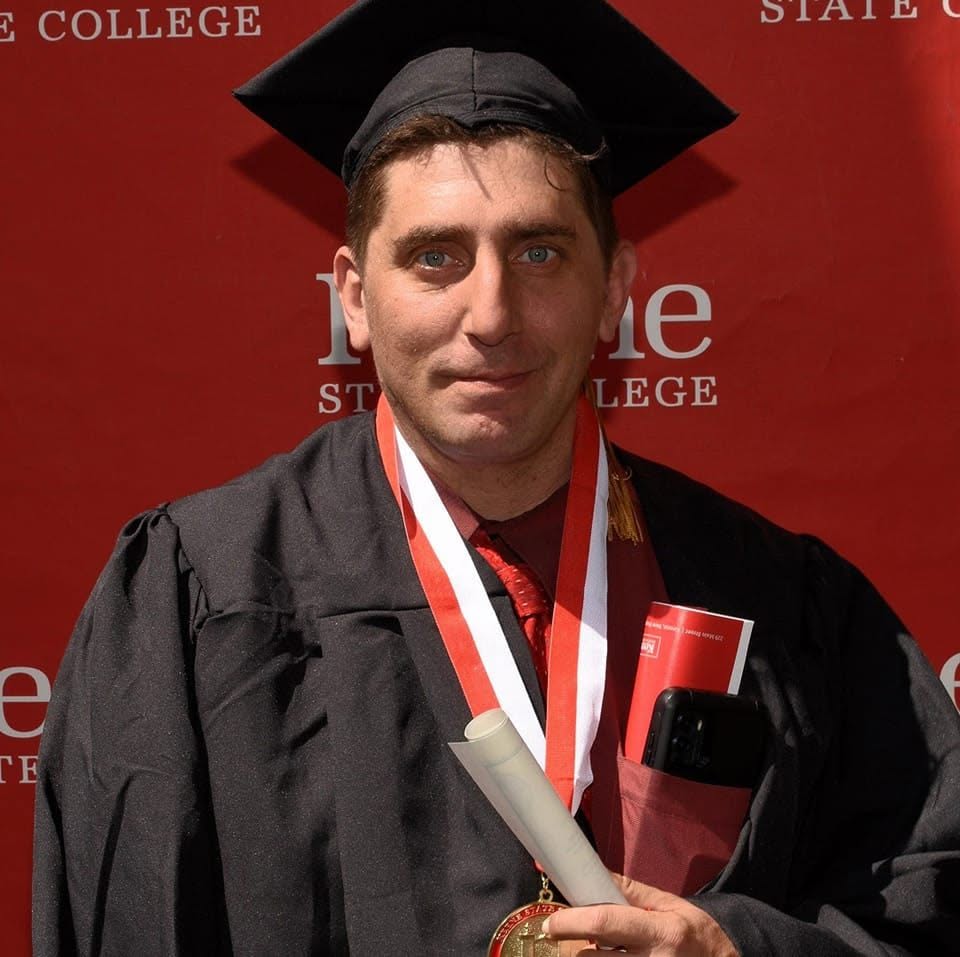 Thomas C. Parisi at his Keene State College graduation, holding his diploma.